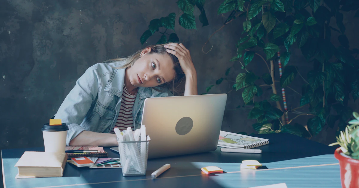 Woman looking stressed while working on her laptop at the office