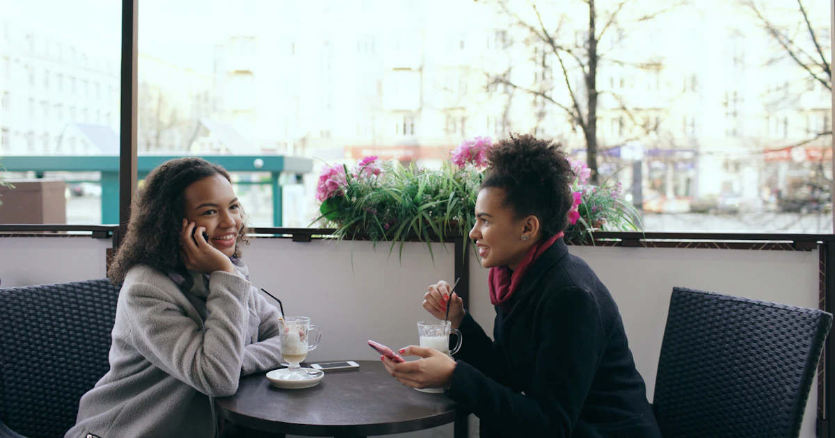 Two women talking over coffee at an outdoor cafe table